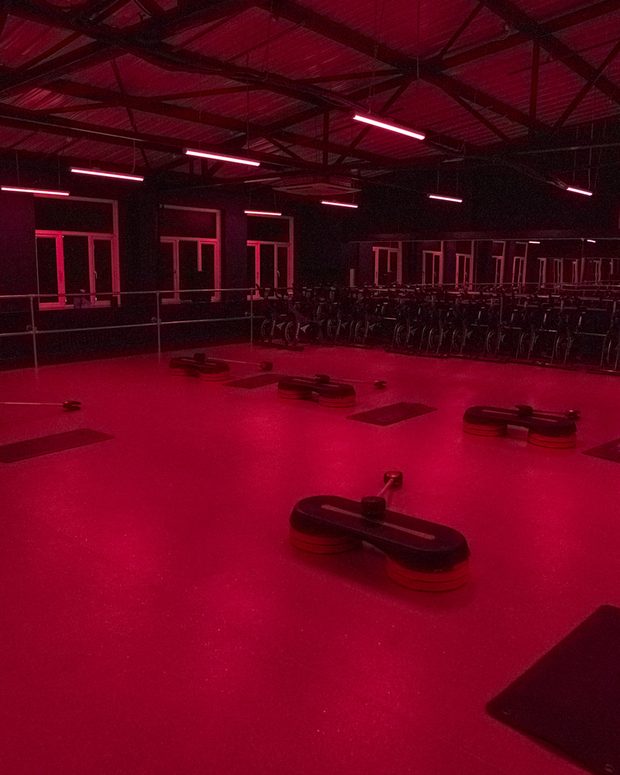 The studio lit red for a class, bikes racked along the back wall